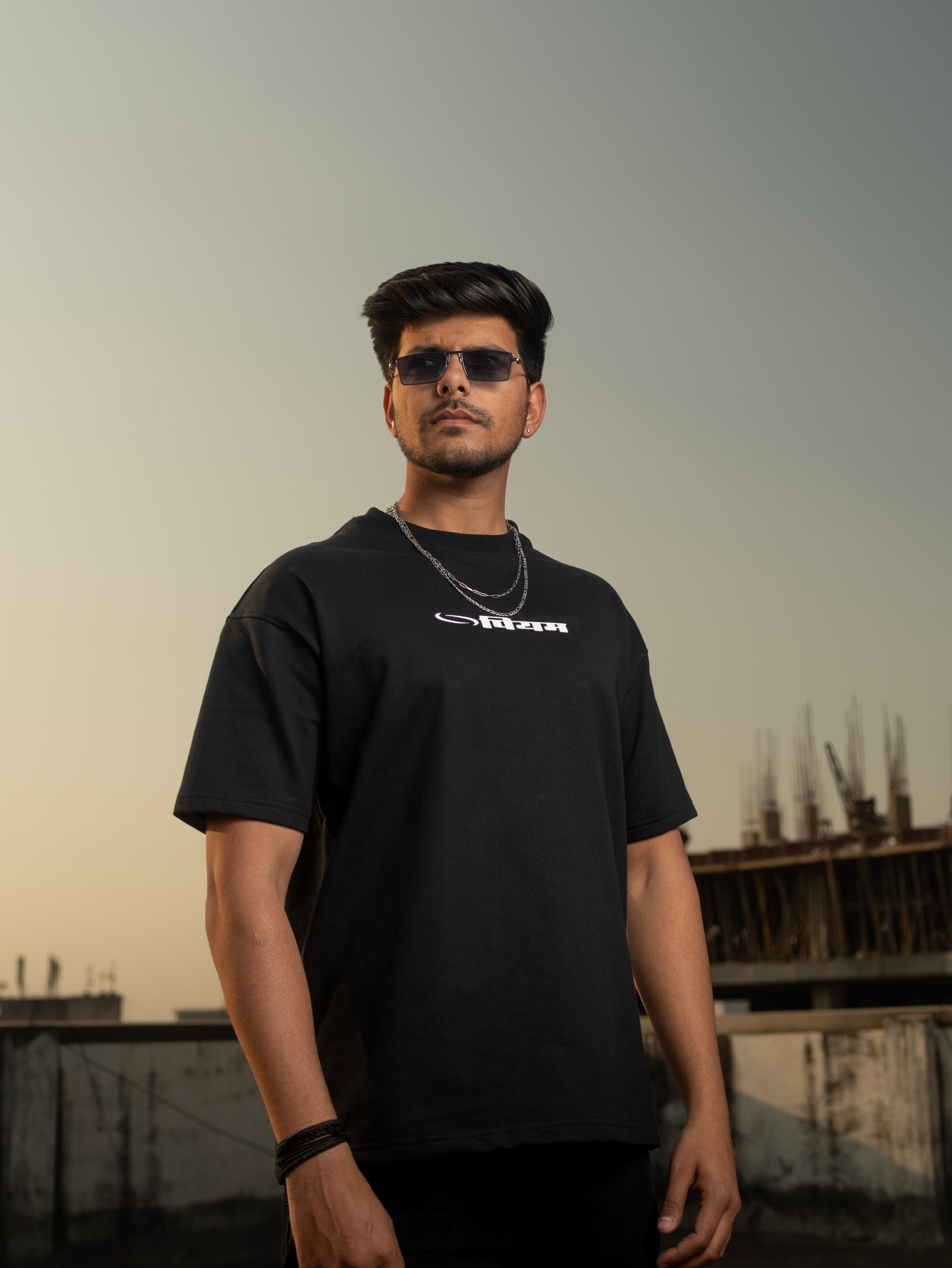 Man wearing a black t-shirt with a logo against an urban backdrop