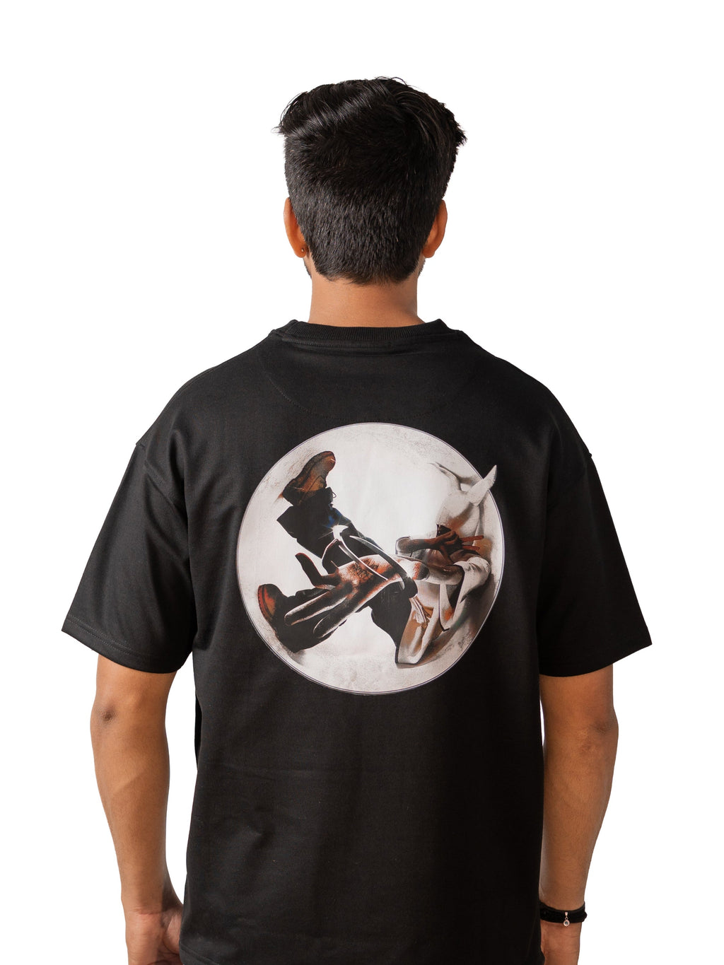 Person wearing a black t-shirt with a graphic design on the back, standing against a white background